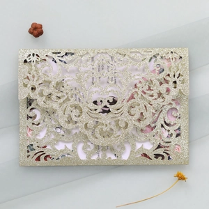Detailed laser-cut gold glitter wedding invitation with elegant floral insert and envelopes