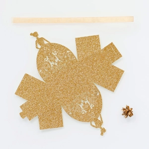 Detail of laser-cut gold glitter favor box with bridal gown silhouette and satin ribbon