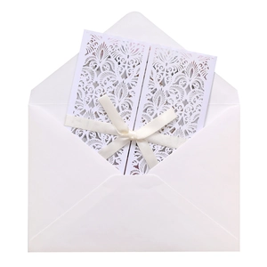 Détail d'invitation de mariage découpée au laser avec un nœud en ruban crème et enveloppe