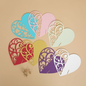 Detailed view of colorful laser-cut hollow heart wine glass place cards for wedding tables
