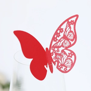 Close-up of laser-cut red paper butterfly decoration for wine glass at wedding parties