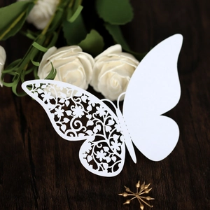 Detail of laser-cut butterfly place card with intricate floral wing on a dark wood background