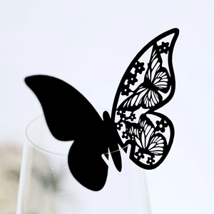 Detail of laser-cut black butterfly place card on wine glass for wedding party