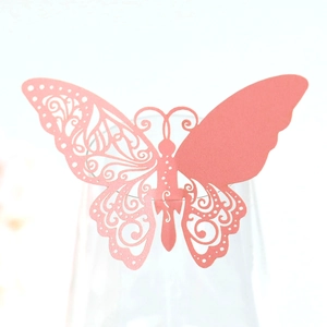 Vue macro d'un papillon en papier rose découpé au laser pour verre de mariage