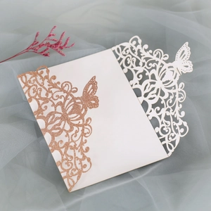 Intricate laser-cut butterfly invitation card with rose gold glitter and white floral patterns