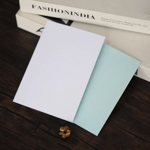 Cartes d'invitation blanc nacré et vert menthe sur une surface en bois sombre rustique