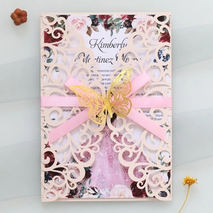 Détail d'invitation découpée au laser avec carte florale, ruban rose et papillon doré