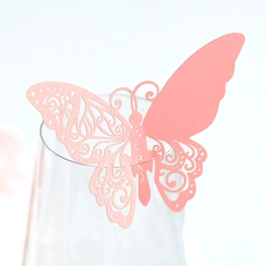 Détail macro du marque-place papillon découpé au laser en rose clair sur le bord d'un verre