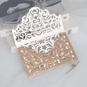 Detail of laser-cut wedding invitation with champagne gold glitter and ivory floral pattern