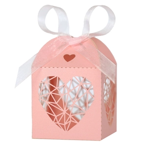 Détail de la boîte à dragées rose découpée au laser avec ruban blanc et motifs de cœur