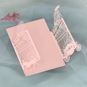 Detail of pink laser-cut wedding invitation featuring a carriage and palace gate design