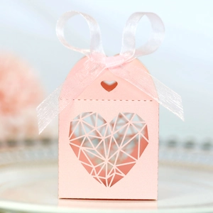 Détail boîte à dragées mariage rose avec motifs cœurs découpés et ruban soyeux