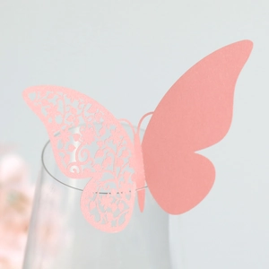 Macro shot of laser-cut pink butterfly paper place card for wine glass rim decoration
