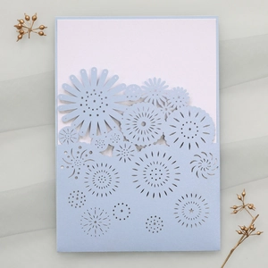Detailed close-up of light blue laser-cut flower invitation with white insert card