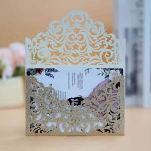 Detail of laser-cut glitter gold wedding invitation with intricate floral hollow pattern