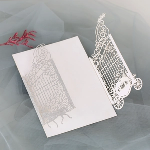 Macro detail of laser-cut wedding invitation featuring elegant silver glitter carriage design