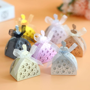 Close-up of elegant laser-cut dress-shaped candy boxes with glitter finish and ribbons
