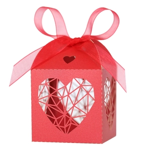 Détail boîte cadeau rouge ajourée cœur avec motifs géométriques et ruban de soie chic