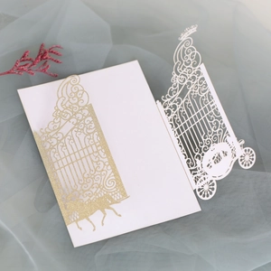 Detail of laser-cut wedding invitation featuring a golden glitter carriage and gate design