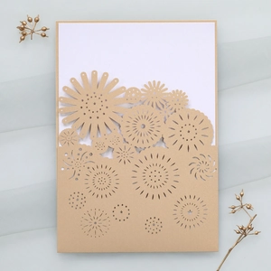 Macro view of gold laser-cut floral wedding invitation with elegant hollow patterns