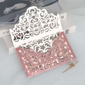 Detail of laser-cut white hollow pattern and pink glitter finish on wedding invitation