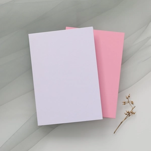 Détail de cartes d'invitation découpées avec papier rose et blanc sur fond de gaze