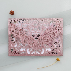 Detail of laser-cut rose gold glitter wedding invitation with elegant floral card