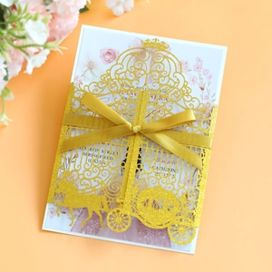 Detail of laser cut gold wedding invitation with a carriage design and silk ribbon bow