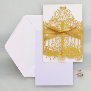 Detail of laser-cut gold glitter wedding invitation featuring carriage design and silk bow