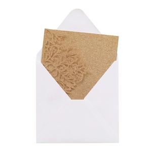 Detail view of gold glitter laser-cut wedding invitation card with a white envelope