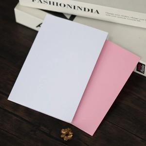 Vue à plat de cartes d'invitation minimalistes blanches et roses sur bois