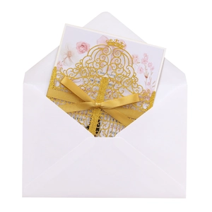 Detail of laser-cut gold glitter wedding invitation with satin bow and floral inner card