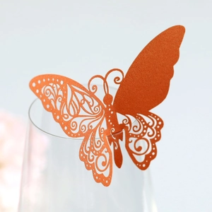 Détail d'un marque-place papillon orange découpé au laser sur le bord d'un verre