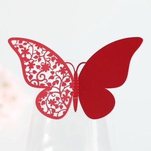 Detail of red laser-cut butterfly place card with floral patterns on a wine glass rim