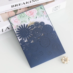 Intricate laser-cut navy wedding invitation with elegant floral patterns and a rose inner card
