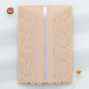 Détail macro du motif floral découpé au laser sur couverture d'invitation mariage dorée