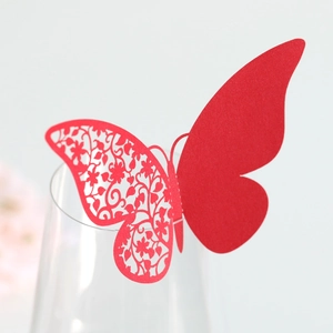 Detailed laser-cut butterfly place card in red paper on a transparent wine glass rim