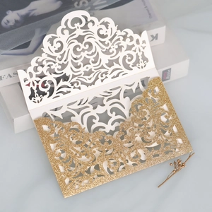 Close-up of laser-cut wedding invitation with elegant gold glitter finish and floral pattern