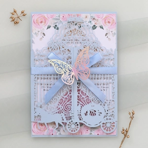 Detail view of light blue laser cut wedding invitation with ribbon and butterfly