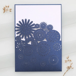 Detail of laser-cut navy blue floral wedding invitation with pearlescent glitter finish