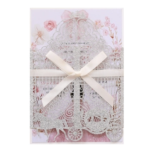 Detail of silver glitter laser-cut wedding invitation with hollow carriage and ribbon