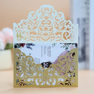 Detail of laser-cut glitter wedding invitation with intricate floral lace and gold shimmer