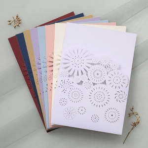 Close-up of laser-cut floral wedding invitations in various elegant pearlescent colors