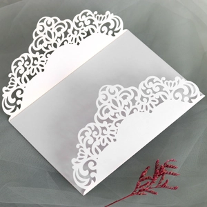 Detail of laser-cut lace floral patterns on white paper wedding invitation envelope