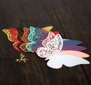 Detailed laser-cut hollow butterfly cards in assorted colors on a wood surface