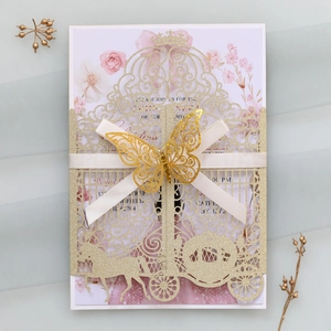 Detailed laser-cut champagne gold wedding invitation with intricate carriage and ribbon