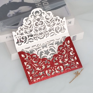 Macro detail of laser-cut wedding invitation with red glitter and white vine patterns