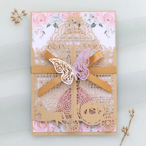 Detail of laser-cut crown and carriage wedding invitation with pink floral card and golden bow