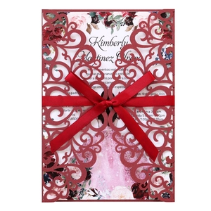 Détail de pochette d'invitation découpée au laser avec nœud rouge et carte florale
