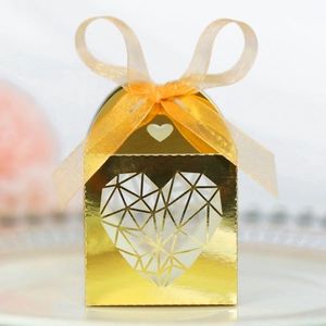Détail d'une boîte à bonbons dorée à motif cœur évidé avec un ruban de satin orange